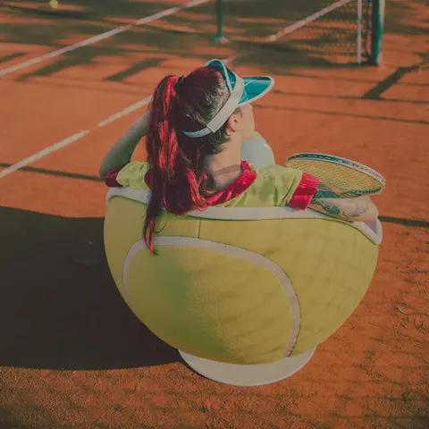Tennis Sessel volley steht am Seitenrand eines Tennisplatzes, eine Person sitzt entspannt darin und verfolgt das Tennisspiel, aus leicht erhöhter Perspektive von hinten fotografiert von lillus