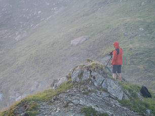 Fotografo in montagna in Val di Fassa con treppiede mentre osserva il paesaggio avvolto dalla foschia