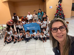 Crianças da Casa de Jacira junto com companheiros posando para foto de grupo com bandeira do Interact Club do Rj Maracanã
