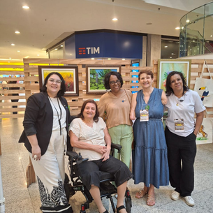 Pres. do Rotary Patrícia Leal  em foto a frente de quadros com outra rotariana, duas artistas especiais que  fazem pintura com a boca e a presidente da Associação