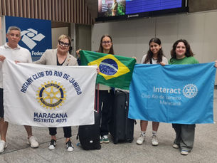 Casal de rotarianos Roberto e Cláudia Reis e as intercambistas Hortense, Gabriela e Olívia com bandeiras do Clube e do Brasil