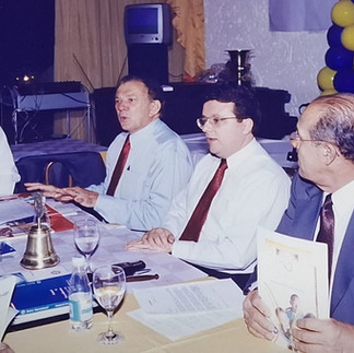 Companheiros sentados à mesa durante reunião da visita de Governador.