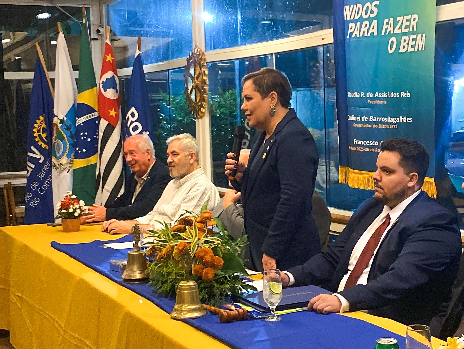 Presidente Cláudia Reis se pronuncia durante reunião, ao centro da mesa presidencial.