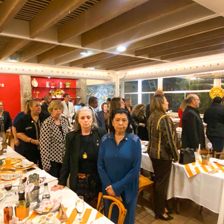 Salão de jantar com muitas pessoas em pé, ao  som do Hino Nacional.