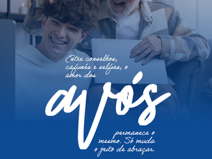 Avô sentado no sofá afagando o cabelo do jovem neto com as mãos de forma divertida. Ambos estão assistindo algo divertido na tela do notebook que está no colo do neto