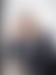 Foto do cabeleireiro Kiko Ricco, homem branco usando óculos de grau retangulares e blazer. Ele tem cabelos grisalhos estilizados. Está encostado em uma poltrona, sorrindo enquanto posa para a foto com uma tesoura para cabelos.