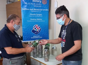 Dois homens rotarianos, observando algumas garrafas de refrigerantes preenchidas com lacres de alumínio