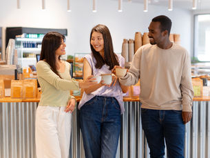 Três jovens brindando com café em espaço de lanchonete na instituição de ensino