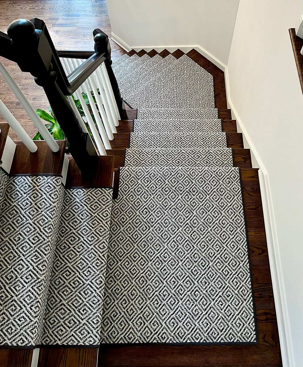 Wooden staircase with black and white patterned carpet runner