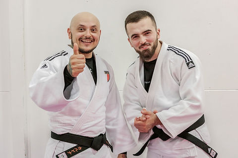 2 men in judo clothes smiling at the camera
