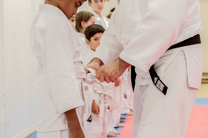 judo teacher tying a student's belt