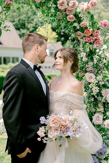 Bride looking at her groom with a floral arch around them