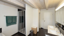 Dusche mit dem dahinterliegende Zugang zum begehbaren Kleiderschrank