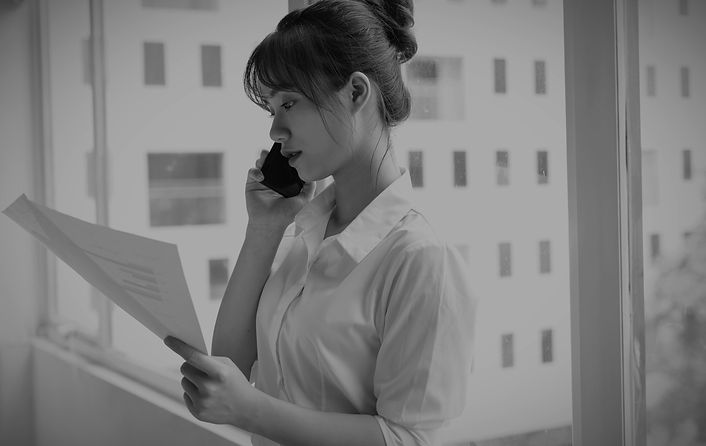 A stressed woman at work, sitting at her desk while talking on the phone, appearing overwhelmed