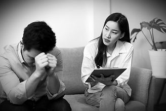 A woman speaking to a man in a therapy session, with the man attentively listening and providing support in a calm and professional setting.