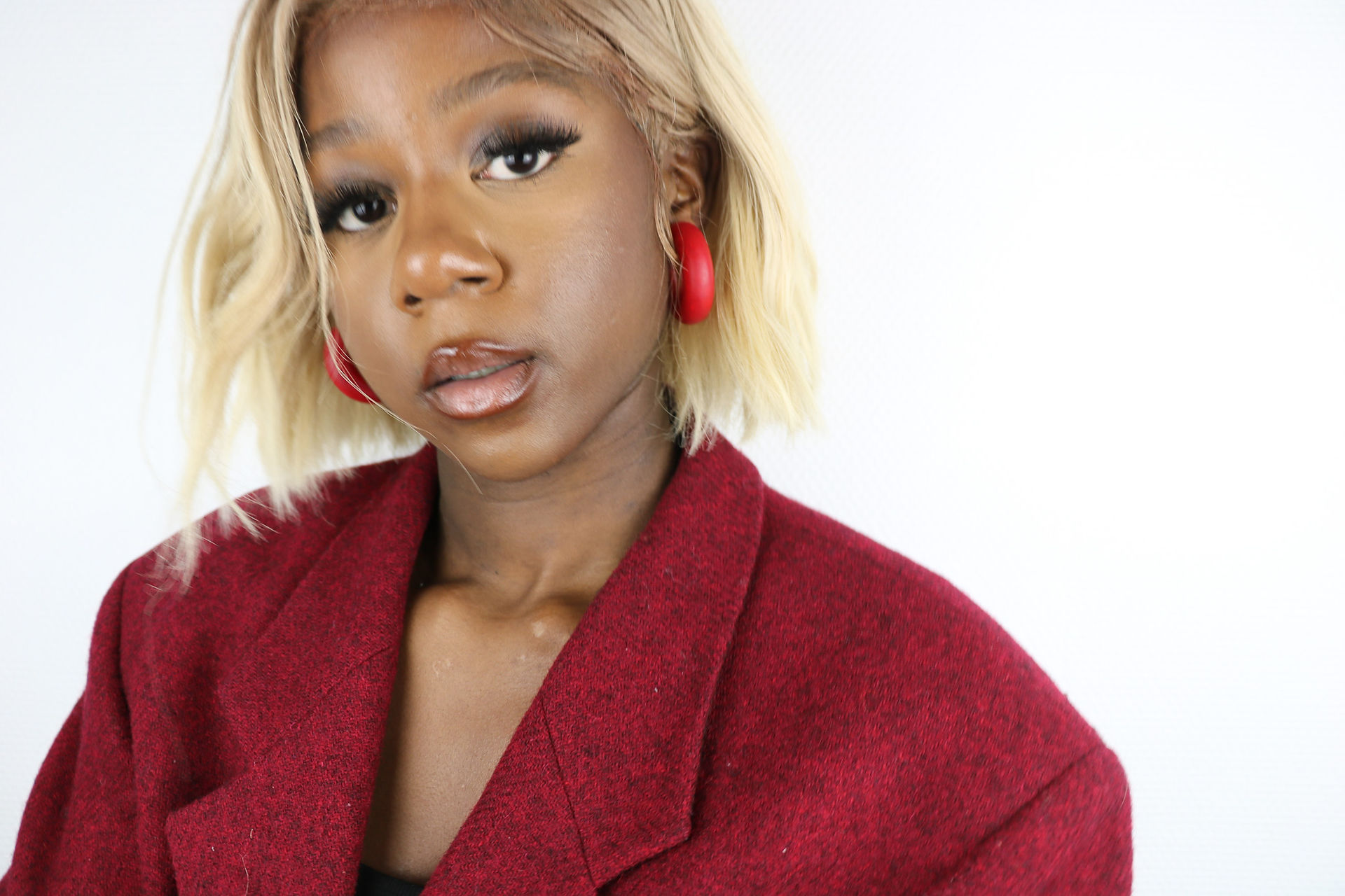 Femme portant des boucles d'oreilles créoles et une veste rouges.