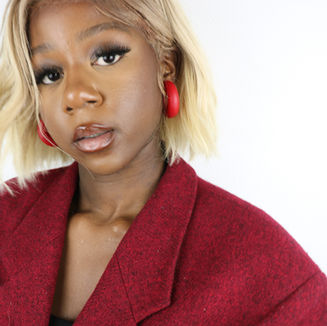Femme portant des boucles d'oreilles créoles et une veste rouges.