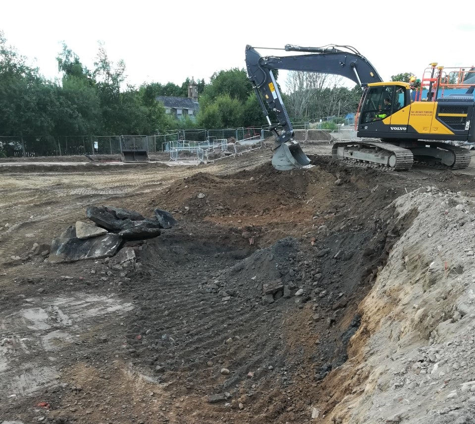 An excavator removing hydrocarbon contaminated soil into a stockpile