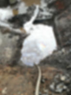 A close up of groundwater inside another trial put showing a rainbow-like oily sheen from hydrocarbon contamination floating on top of the water