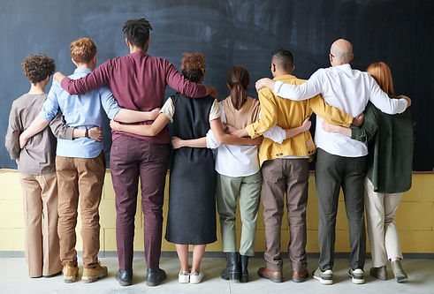 8 people from different backgrounds standing with their backs towards us holding each other backs