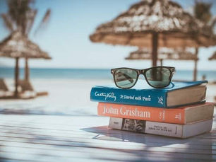 Sunglasses sitting on pile of books at the beach