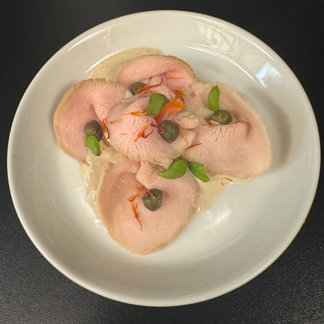 Vitello Tonnato – zarte Kalbfleischscheiben in cremiger Thunfischsauce, garniert mit Kapern, Basilikumblättern und feinen Safranfäden – klassisches italienisches Vorspeisen-Gericht.