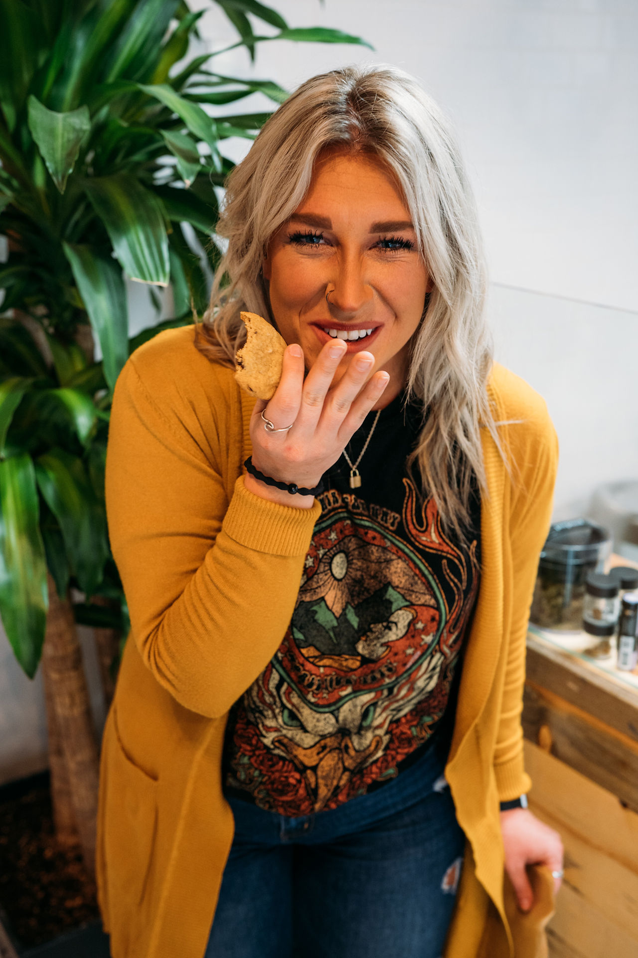 A photo grid showcasing scenes from a cannabis dispensary. The images feature close-up shots of healthy cannabis plants, customers browsing products, and people enjoying cookies displayed in glass jars. The grid captures the vibrant, friendly atmosphere of the dispensary, blending cannabis culture with a sense of community and enjoyment.