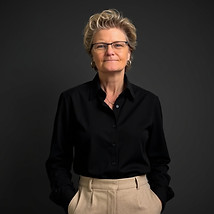 Woman with short blonde hair, glasses, black shirt, beige pants. Robin Kennedy, Founder & Chief Creative Architect