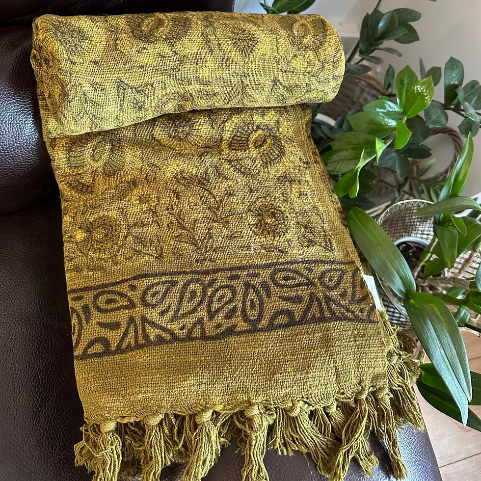 Hand-block printed olive-yellow cotton throw with golden undertones and decorative tassels draped on a sofa.