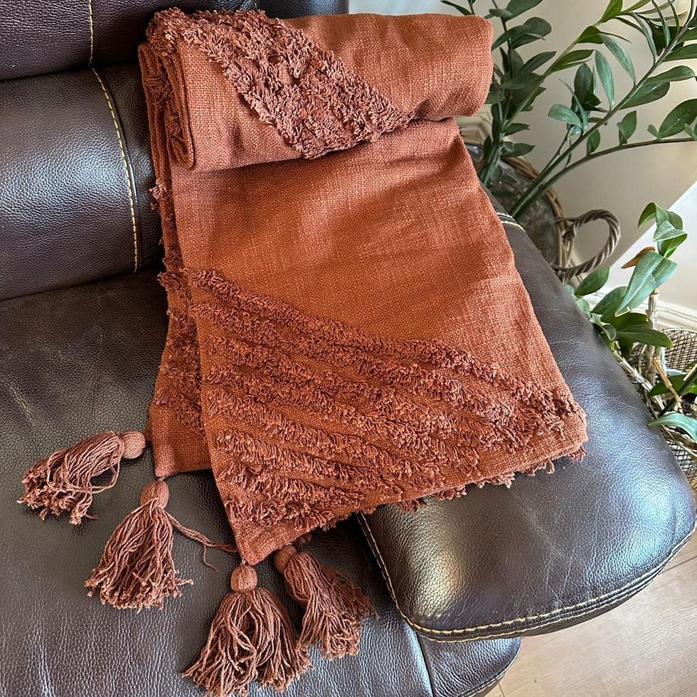 Close-up of a handloomed cotton throw with raised tufted geometric patterns and soft fringed edges.