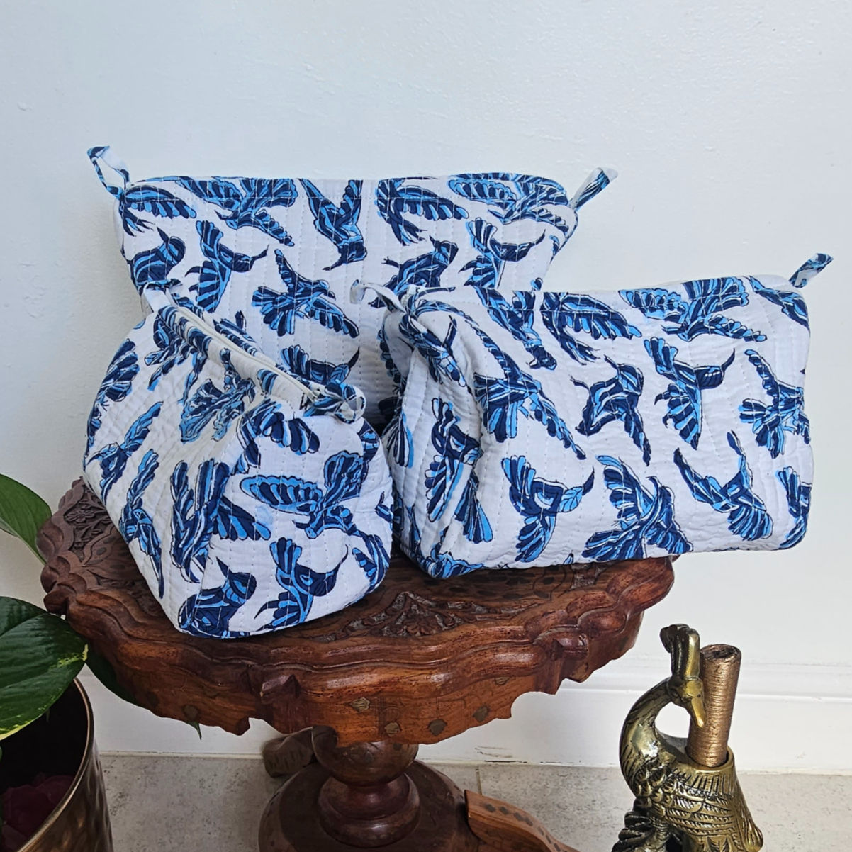 hree stacked hand-block printed wash bags with indigo bird motifs on a white background.