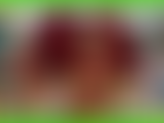 Carnival dancers in vibrant red and gold costumes, with feathered headdresses, smile and dance joyfully on a colorful street parade.