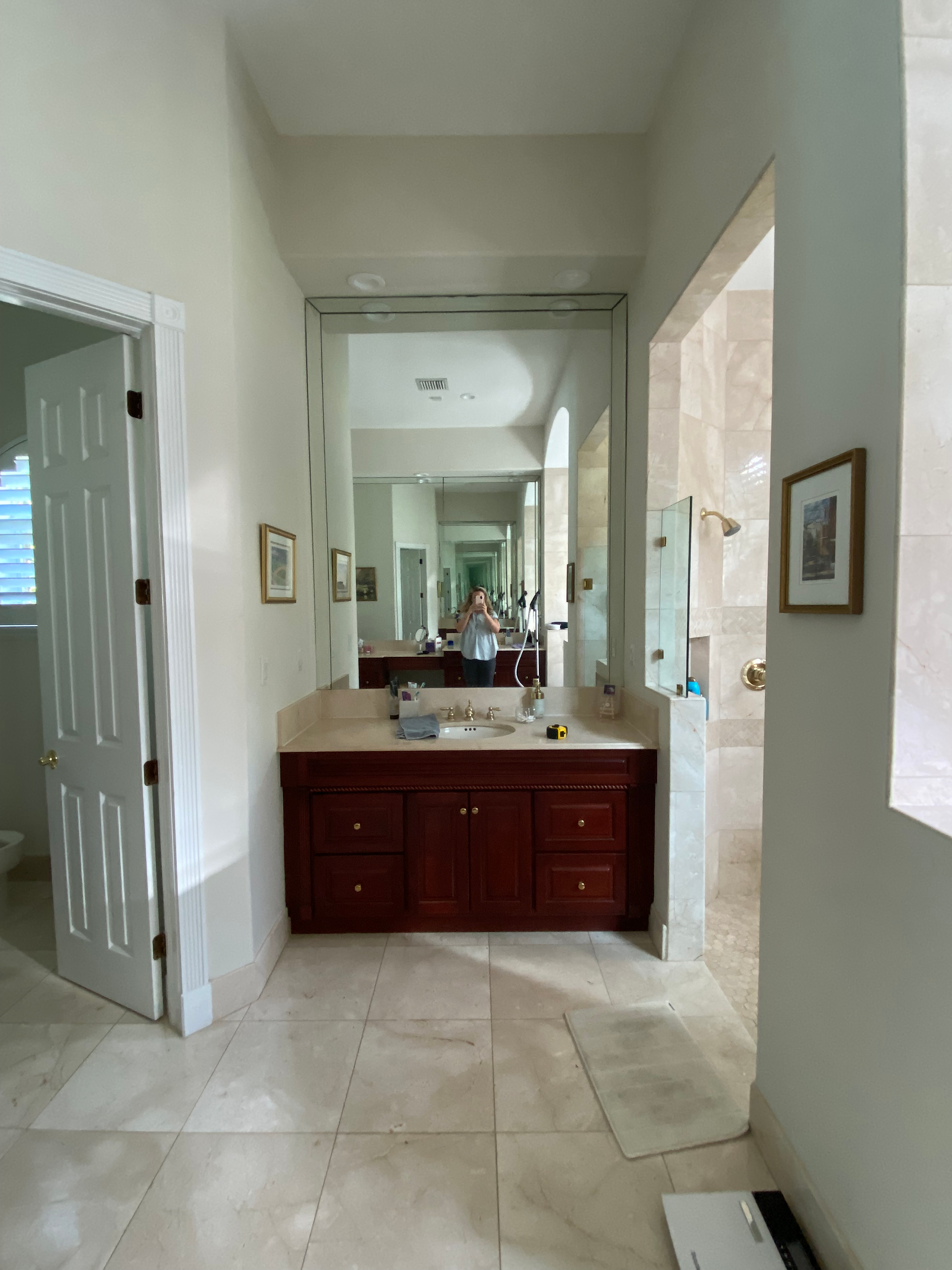 A dark and dated bathroom with wood vanities and travertine tiles
