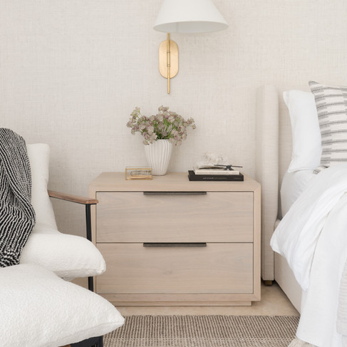 An upholstered bed and oak nightstands in a sophisticated neutral bedroom designed by Miami Interior Designer The Habitat Collective