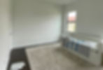 The before photo of a nursery, with blank white walls and a beige rug.