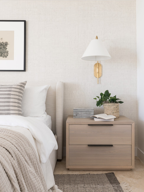 An upholstered bed and oak nightstands in a sophisticated neutral bedroom designed by Miami Interior Designer The Habitat Collective