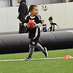 Young boy in black uniform playing football