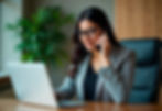 Business woman working on laptop and talking on phone at office desk