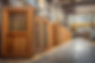 Wooden doors stacked in a warehouse with yellow line markers and equipment.