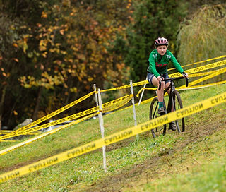 A young rider climbing a grass bank at the Devo Cross cyclocross bike race in Vancouver