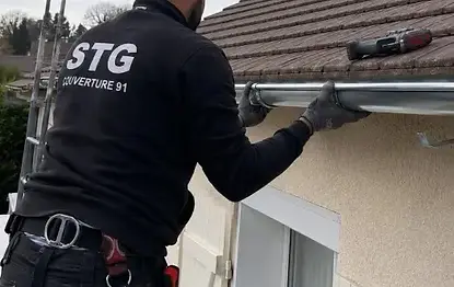 Un couvreur zingueur STG Couverture 91 pose une gouttière en zinc sur une maison dans le sud de l'Essonne