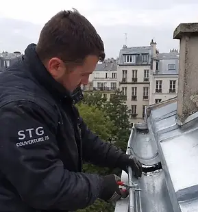Couvreur zingueur STG Couverture 75 réparant une gouttière zinc sur un immeuble à Paris 19