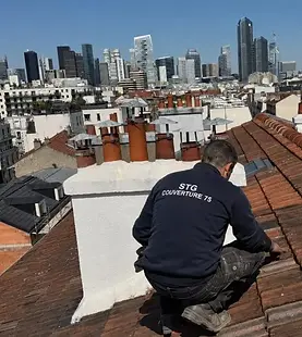 Couvreur STG Couverture 75 inspectant une toiture en tuiles avant rénovation dans le 17e arrondissement de Paris.