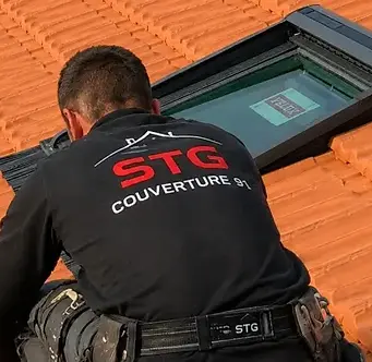 Un couvreur contrôle l'étanchéité d'une fenêtre de toit après la pose d'un Velux