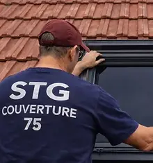 Couvreur STG Couverture 75 installant une fenêtre de toit Velux sur une toiture en tuiles mécaniques dans le 19ᵉ arrondissement de Paris