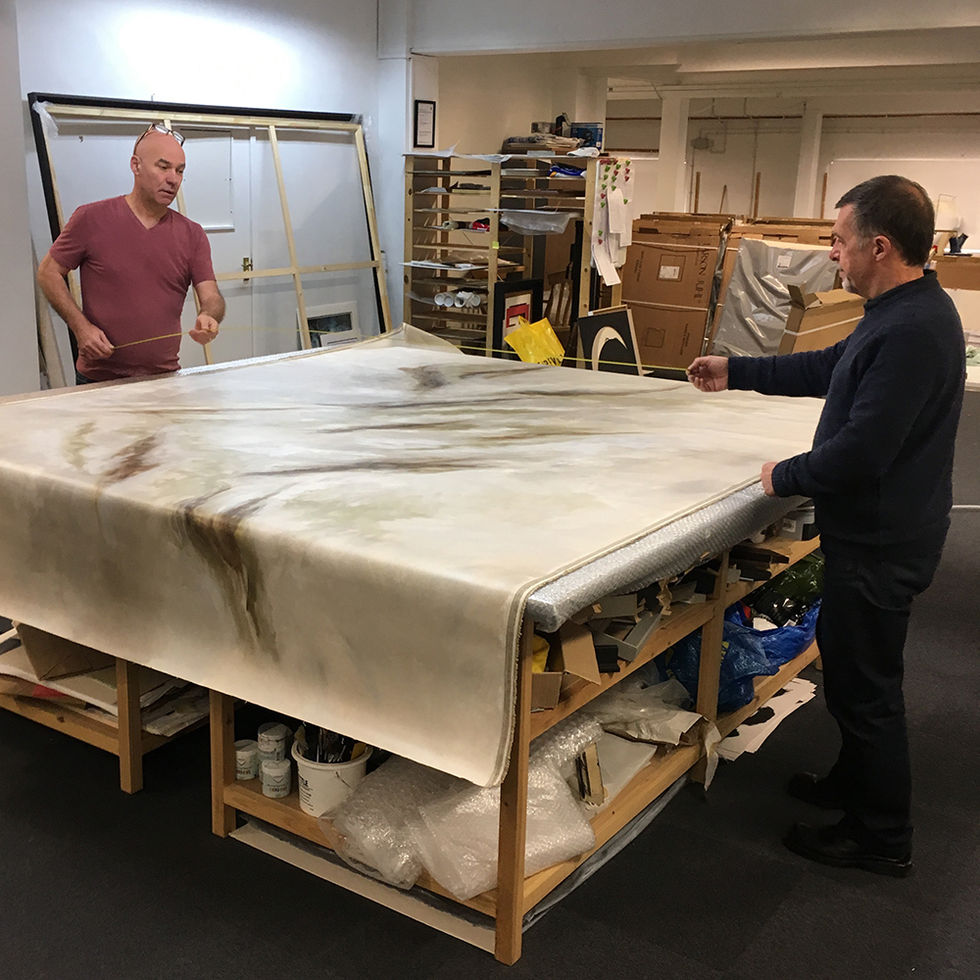two men are working on a large piece of art in a warehouse