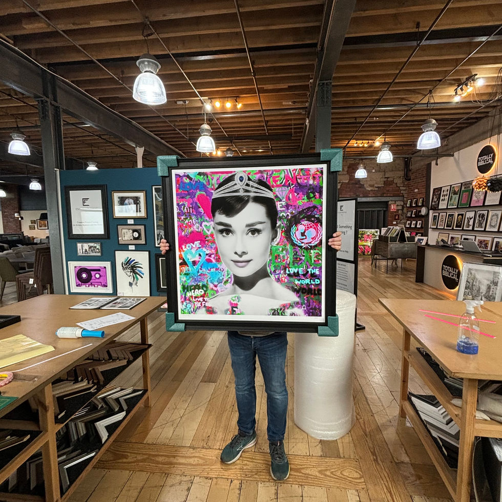 a man is holding a framed picture of audrey hepburn