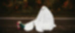 A young person wearing a ghost costume on roller blades has fallen on the road to illustrate the art and joy of playful experimentation.