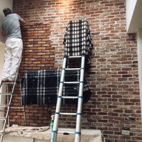 man installing a brick slip wall with an extendable ladder 