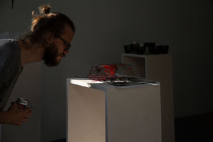 Exhibition view of two-headed woman motif printed on silk and glass, referencing Izhorian embroidery traditions.